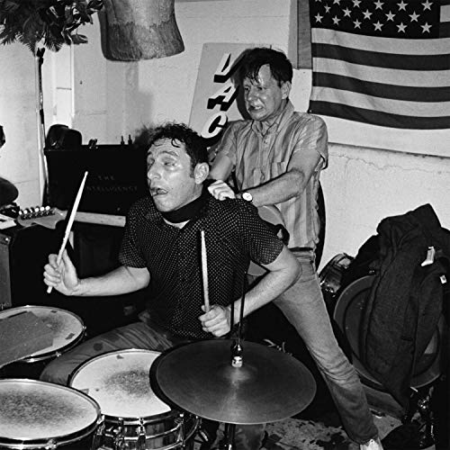 Black and white photo of two men performing with drums and sticks.