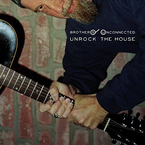 Man playing acoustic guitar, brick wall background, album title text overlay.