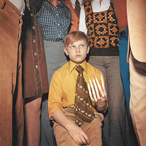 A boy in a yellow shirt holds four plastic forks, surrounded by adults' torsos.