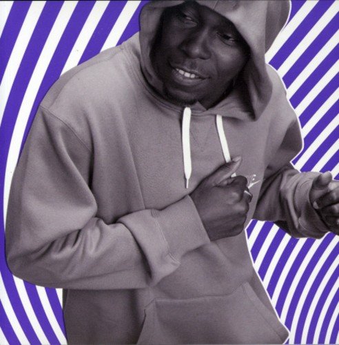 Man in a gray hoodie against a purple and white striped background.