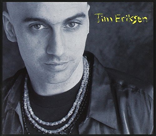 Black and white portrait of man wearing multiple necklaces, with yellow text "Tim Eriksen" on top right.