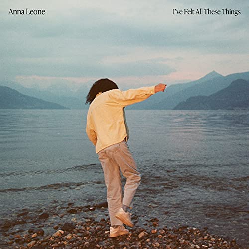 CD cover: Woman with outstretched arm facing a misty lake and mountains.