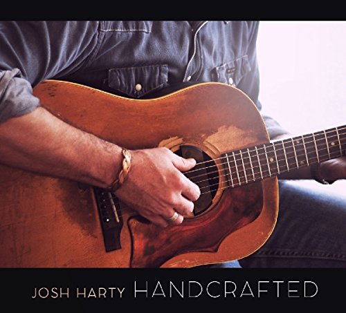 Man holding a worn acoustic guitar, with text "Josh Harty Handcrafted" below.