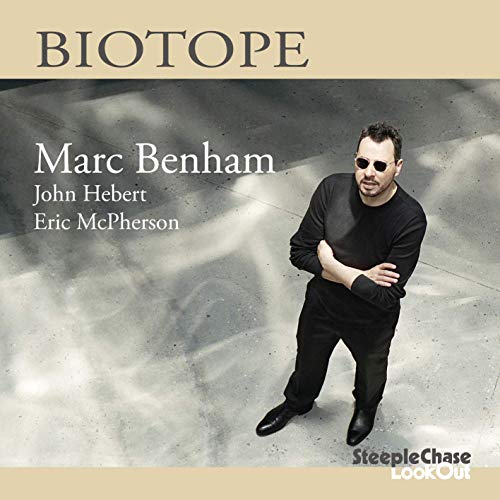 "Album cover featuring a man in black standing on a concrete floor."