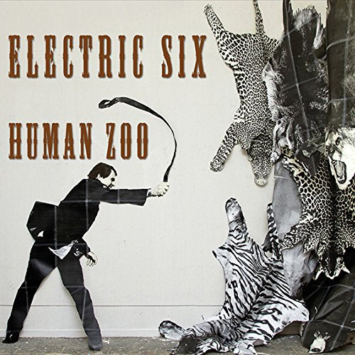 "Album cover with man in suit whipping leopard and zebra skins on the ground."