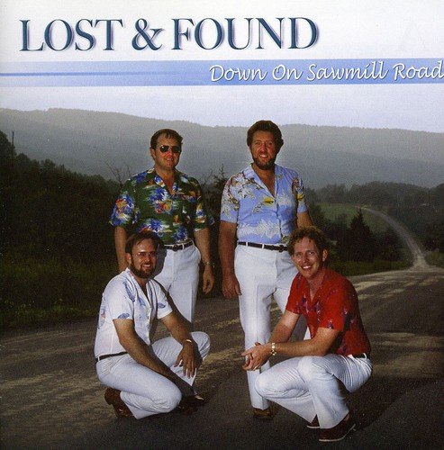 "CD cover featuring four men posing on a road with a mountain landscape."