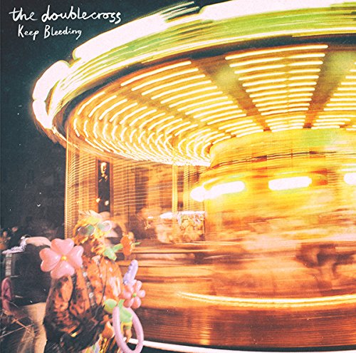 Album cover with a blurry, lit carousel and floral decoration at night.