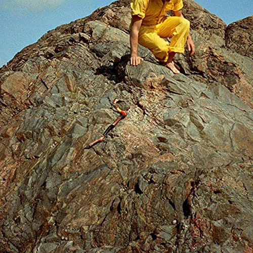 Person in yellow suit sits on a large, textured rock formation.
