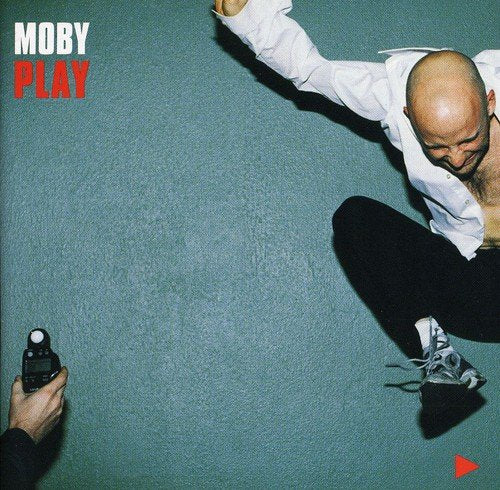 The image depicts a man on a green floor with a camera.