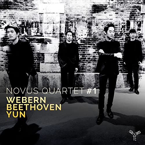 Novus Quartet members in dark clothing stand before a brick wall.