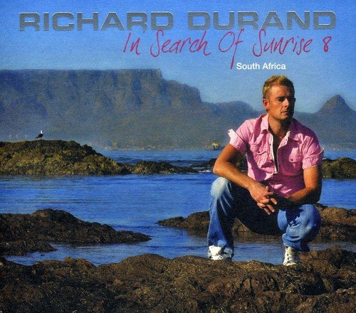 "CD cover with man crouching on rocks, pink shirt, and mountainous background."