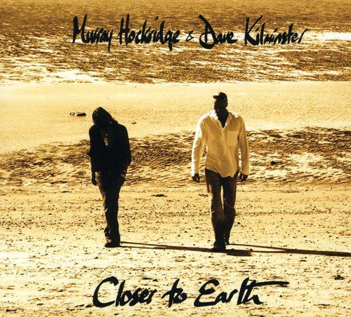 "CD cover featuring two men walking on a sandy beach, sepia-toned image."