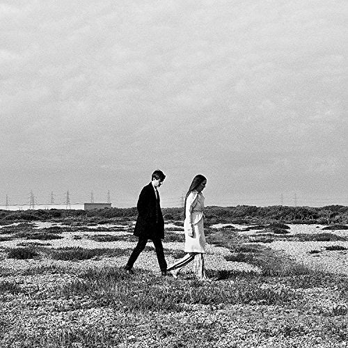 Black and white image of man and woman walking on a rocky field.