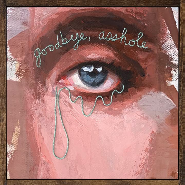Painted eye with tear-shaped embroidery and handwritten text on pink background.