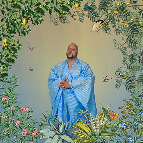 Man in blue robe meditating amidst lush tropical foliage and birds.