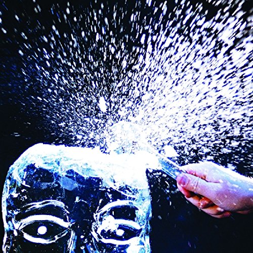 A hand brushes snow off a stone face sculpture, against a dark background.