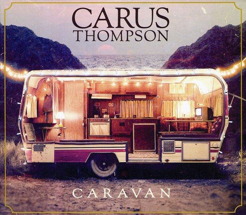 "Album cover featuring a caravan with interior lights on, near mountains and water."