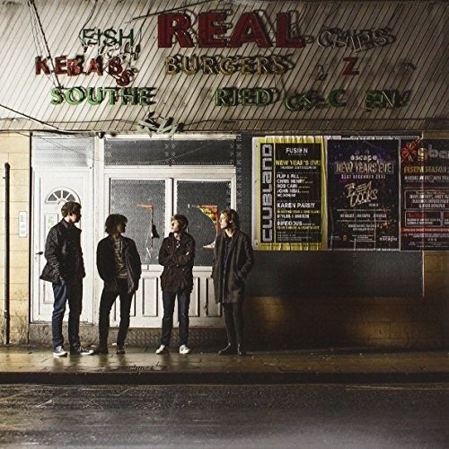 Four men stand outside a shopfront with illuminated signs.