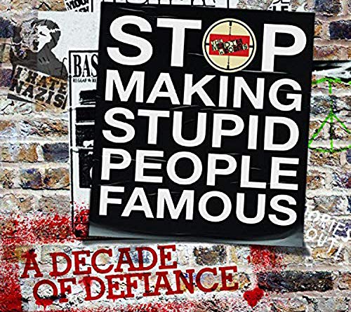 "CD case with black cover and white text, against a graffiti-covered brick wall background."