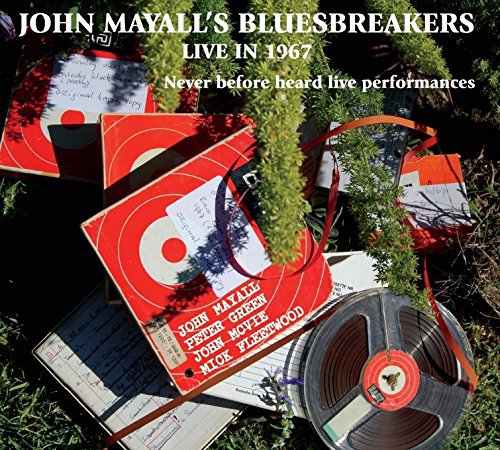 Vinyl record and album covers with red and white design, surrounded by greenery.