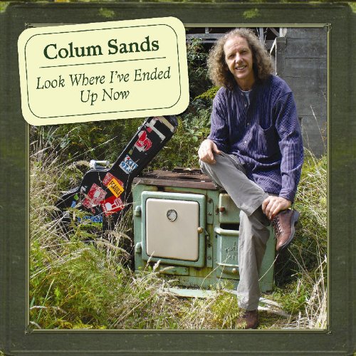 "Album cover with man sitting on an old fridge, guitar beside him."