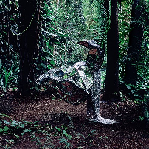 Mosaic donkey sculpture stands in a lush, green forest setting.