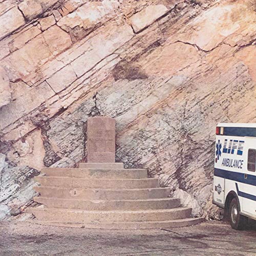Steps lead to a monument before a rocky cliff and ambulance.