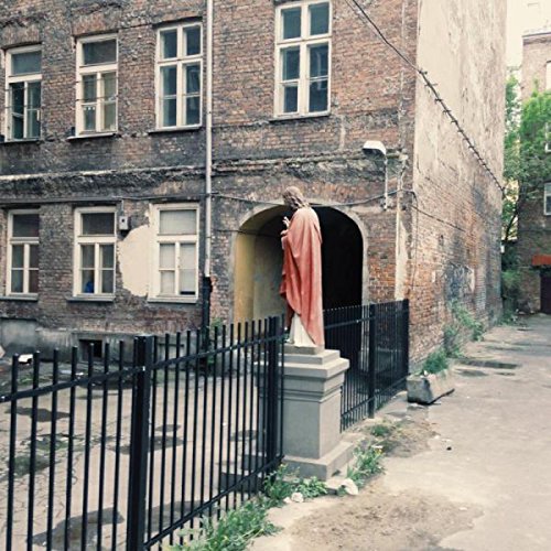 A vinyl record sleeve featuring a statue of a saint in a brick alcove.