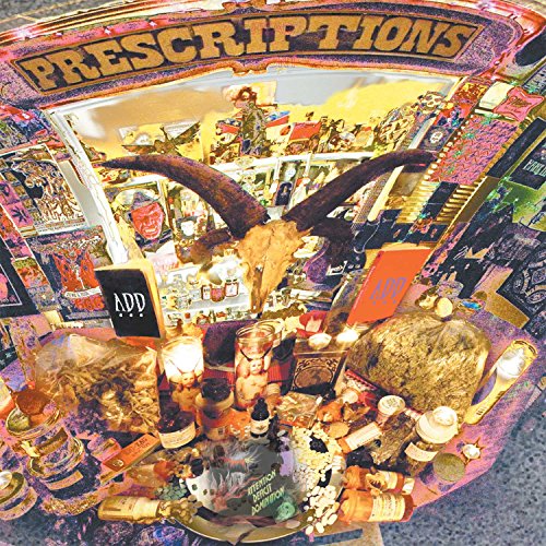 A cluttered table with various objects and a sign reading "prescriptions" in gold letters.