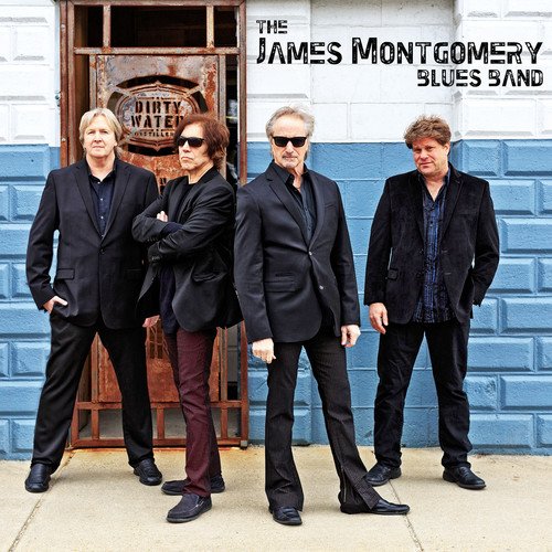 "Album cover featuring four men in black standing in front of a blue and white wall."