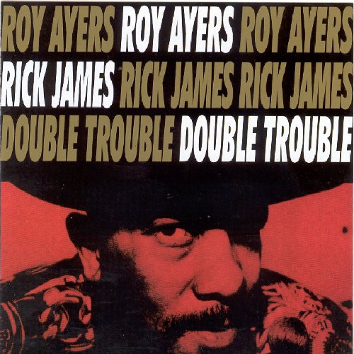 "Album cover with a man in a hat, red and black tones, artist names and title."