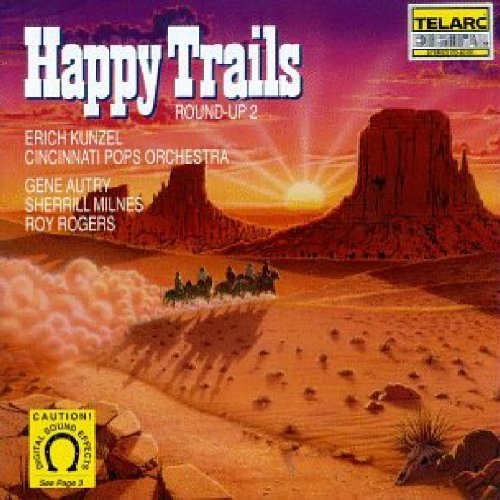 The image depicts a CD cover for "Happy Trails Round-Up 2" with a desert landscape and cowboys on horseback. A concise description of the image is: "CD cover with cowboys riding horses in a desert landscape at sunset."