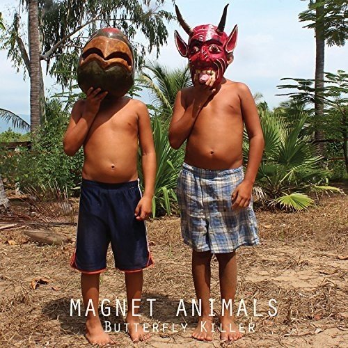 Two shirtless boys wearing colorful, horned masks in a tropical setting.
