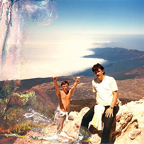 Two men on a mountaintop with a hazy, colorful landscape.