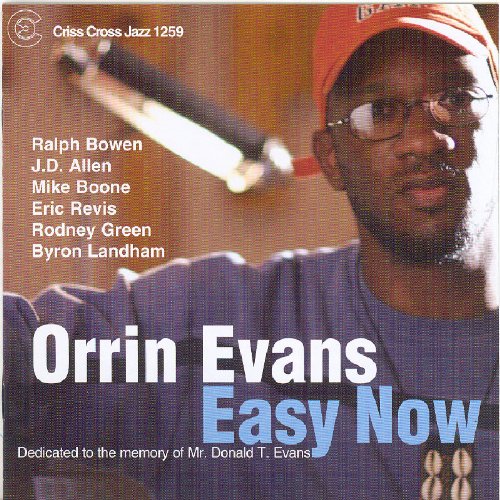 "Orrin Evans album cover featuring a man wearing glasses and an orange cap."