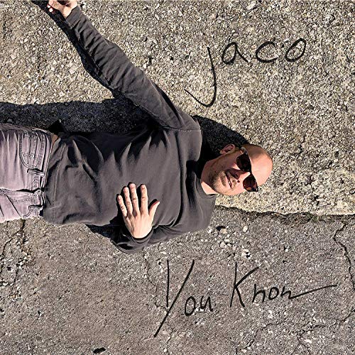 "Man lying on cracked pavement with 'Jaco You Know' written beside him."