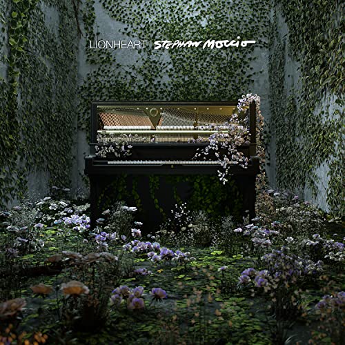 An open piano surrounded by flowers and ivy in a stone-walled courtyard.
