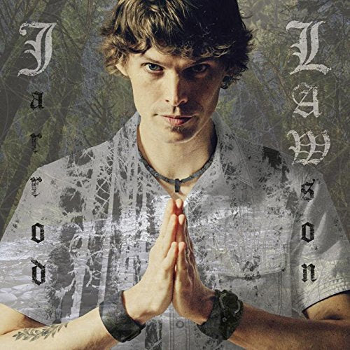 "Man with brown hair and hands clasped together, wearing a patterned shirt and necklace."
