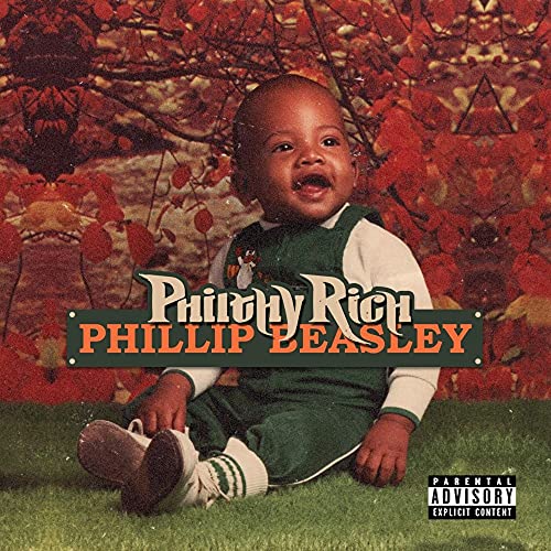 "Album cover featuring a baby in green sitting on grass with red foliage behind."