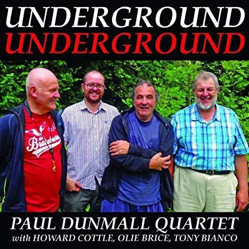 "CD cover with four men standing together, smiling, against a green background."
