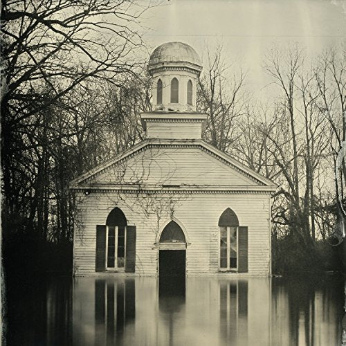 The alt text for the image is: "Flooded church with a domed tower, surrounded by bare trees."
