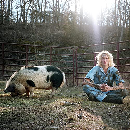 Person and pig sit near a rusty metal fence in sunlight.