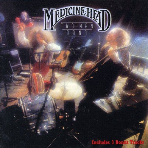 "Album cover with two musicians performing on stage, surrounded by instruments and bright lights."