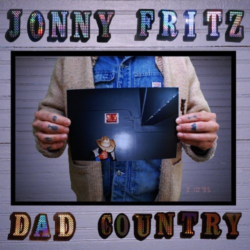 "Album cover with a man holding a vinyl record, against a brick wall."
