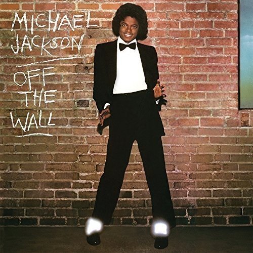 Michael Jackson in a tuxedo posing in front of a brick wall.