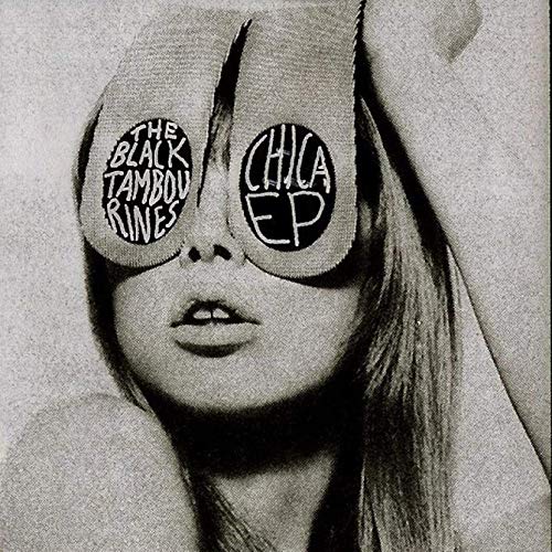 Black and white portrait of a woman with tambourines over her eyes.