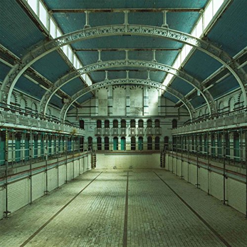Empty indoor swimming pool with tiled walls and arched glass ceiling.