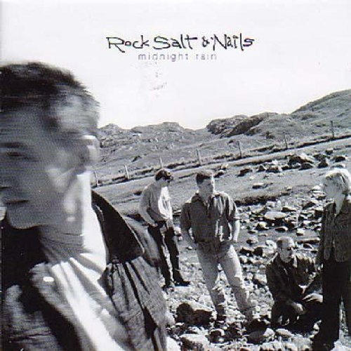 "Black and white album cover featuring a group of men in a rocky landscape."