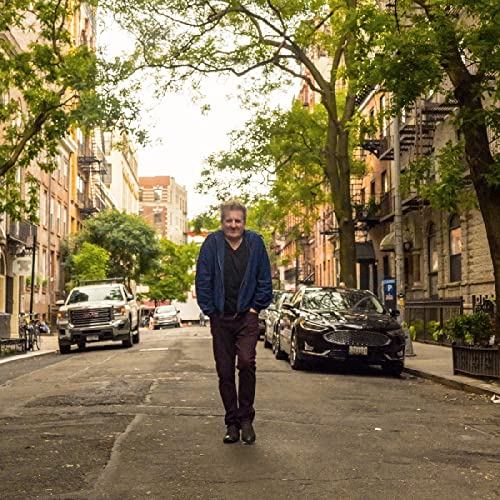 Man in blue jacket standing on a city street, album cover.