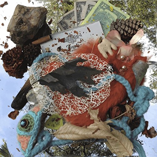 Collage of found objects—snake head, doll, money, lace—against a blue sky.